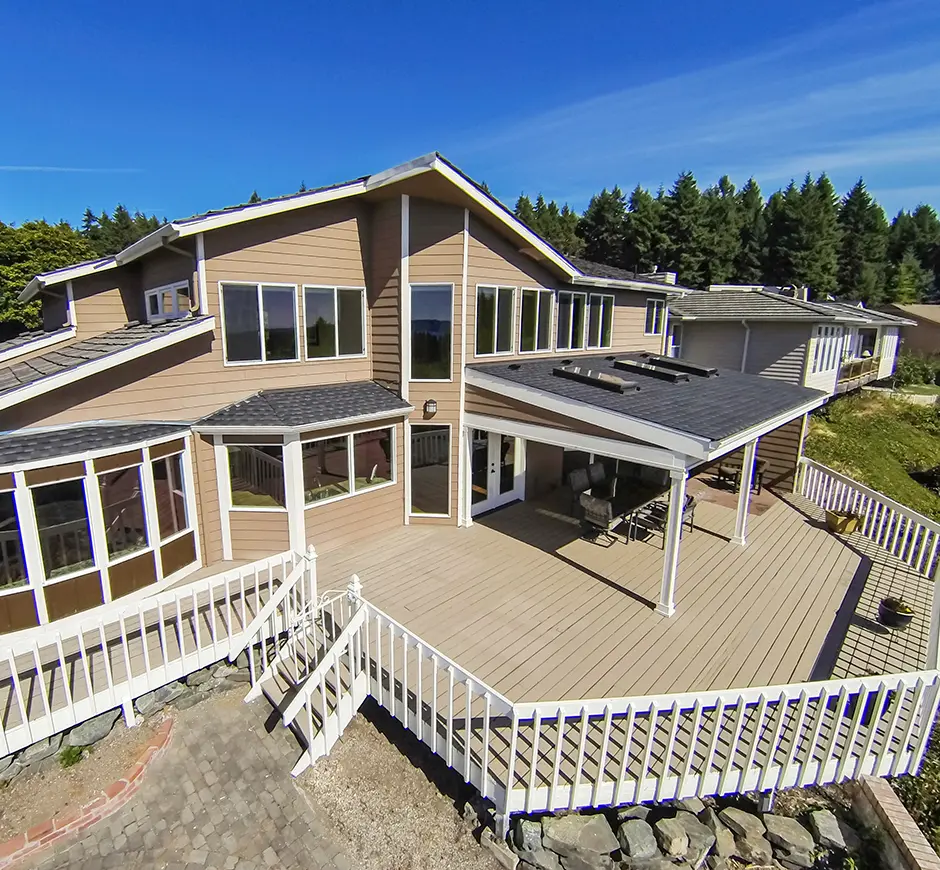 A large deck building project with white railing and wood floorboards painted beige