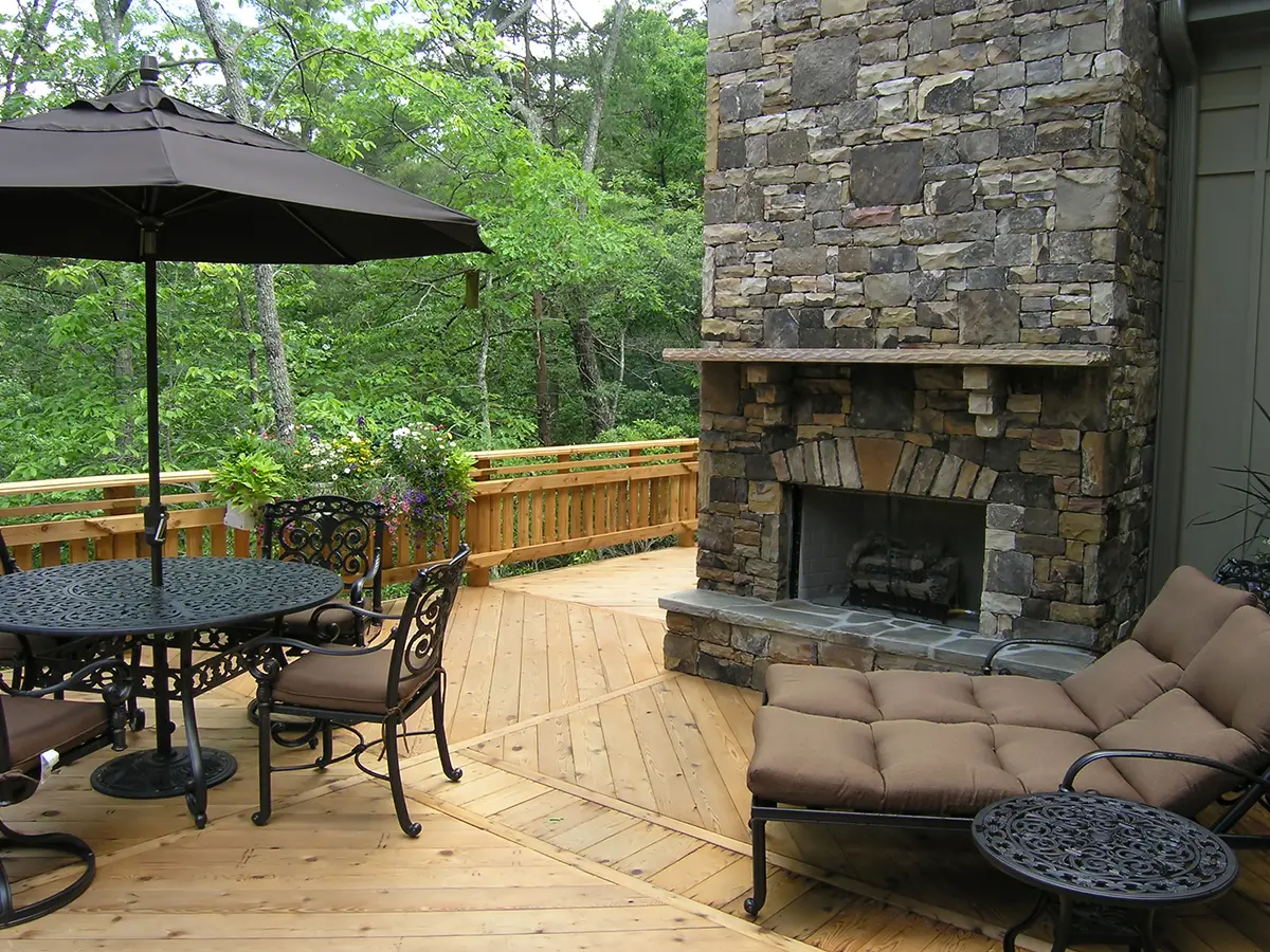 A wood deck with a fireplace and outdoor furniture