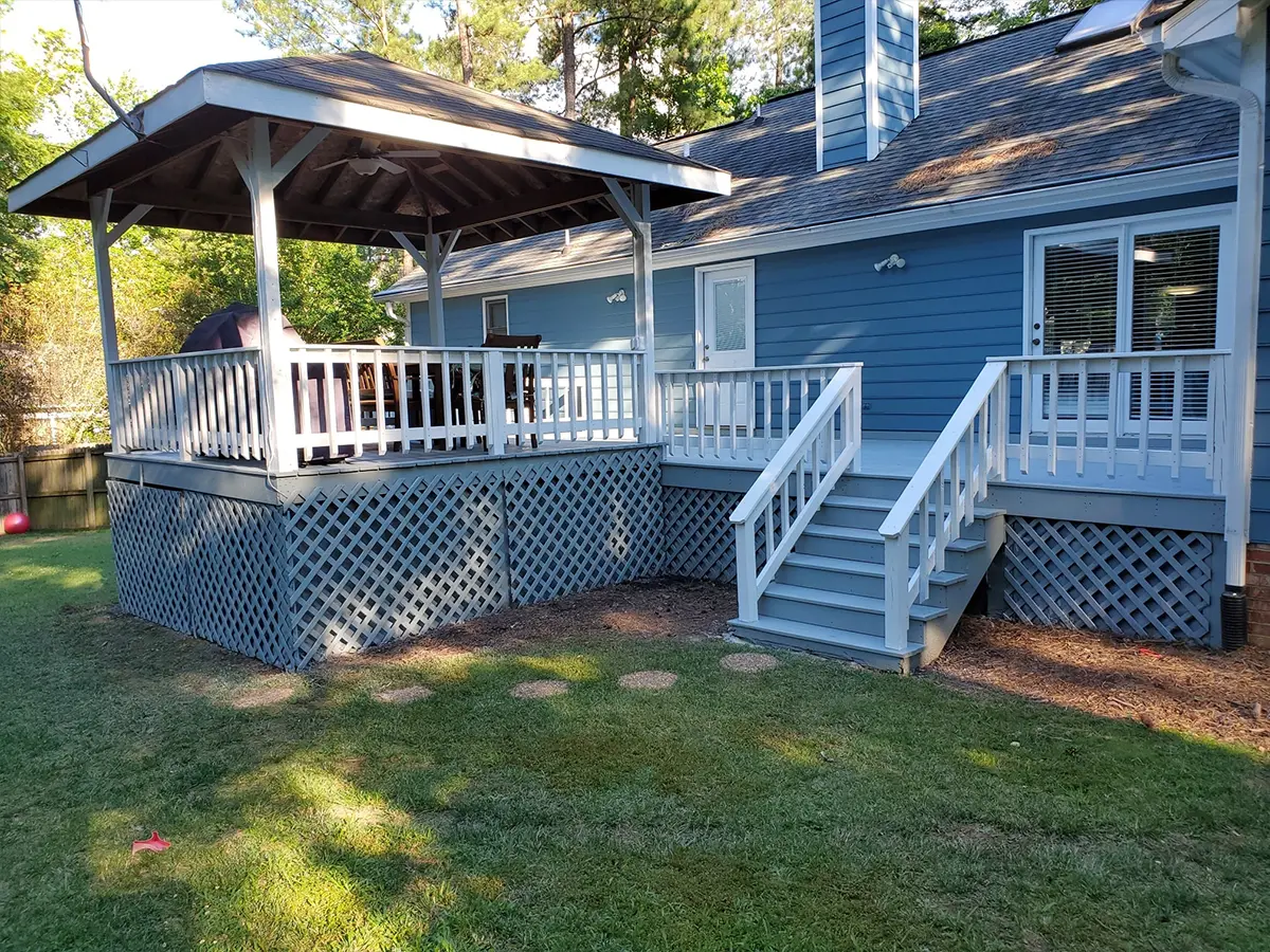 A beautiful wood deck painted white and light blue and a small pergola with a roof