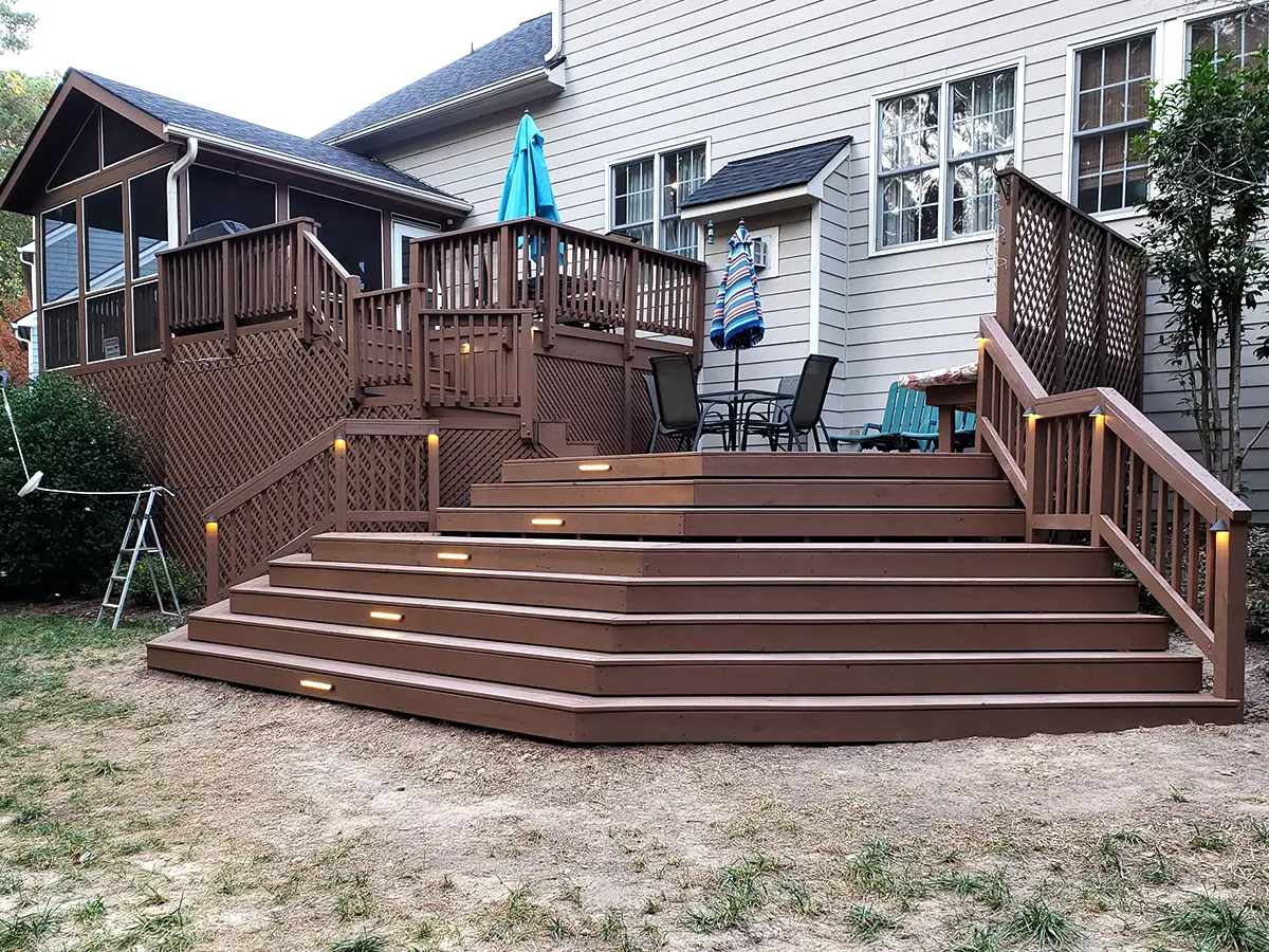 a beautiful and large beige composite deck with stairs lighting