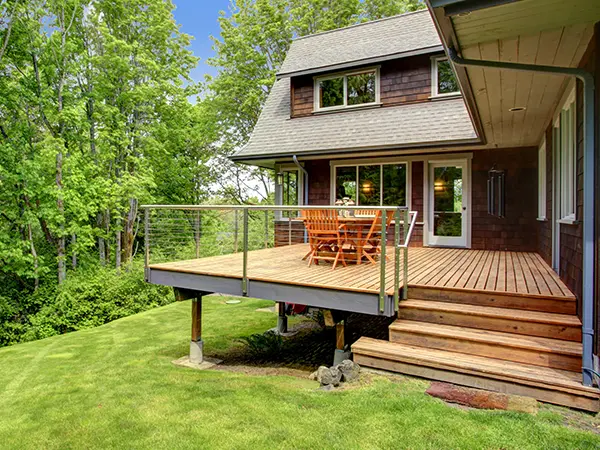 A wood deck on a slope with steel string railing