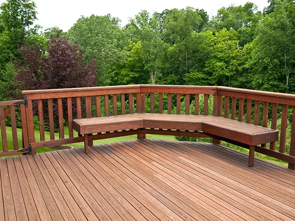 A large wood deck with built-in seating and railing