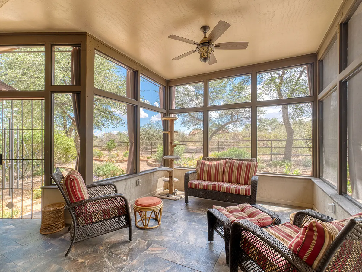 A screened-in porch with tile floor and outdoor furniture