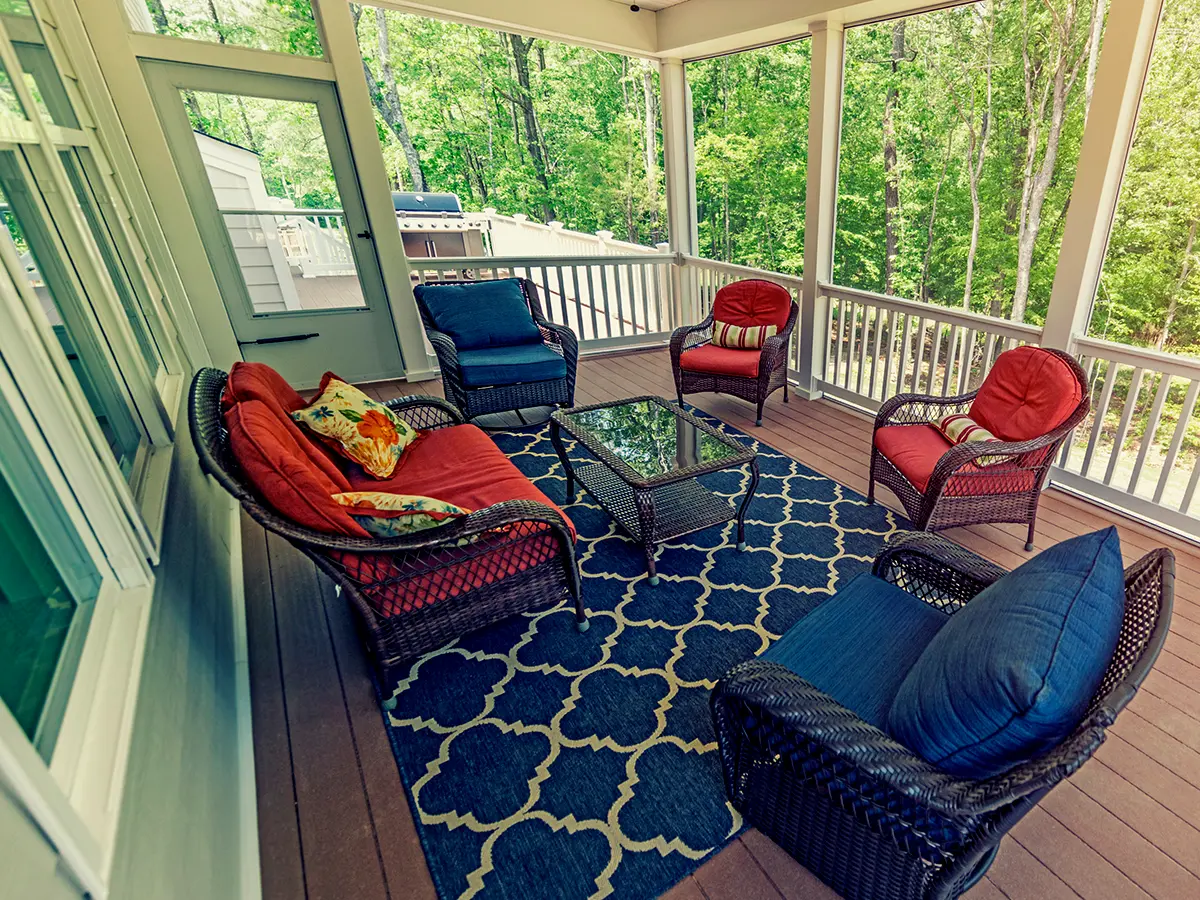 A screened-in porch with white railings and outdoor furniture