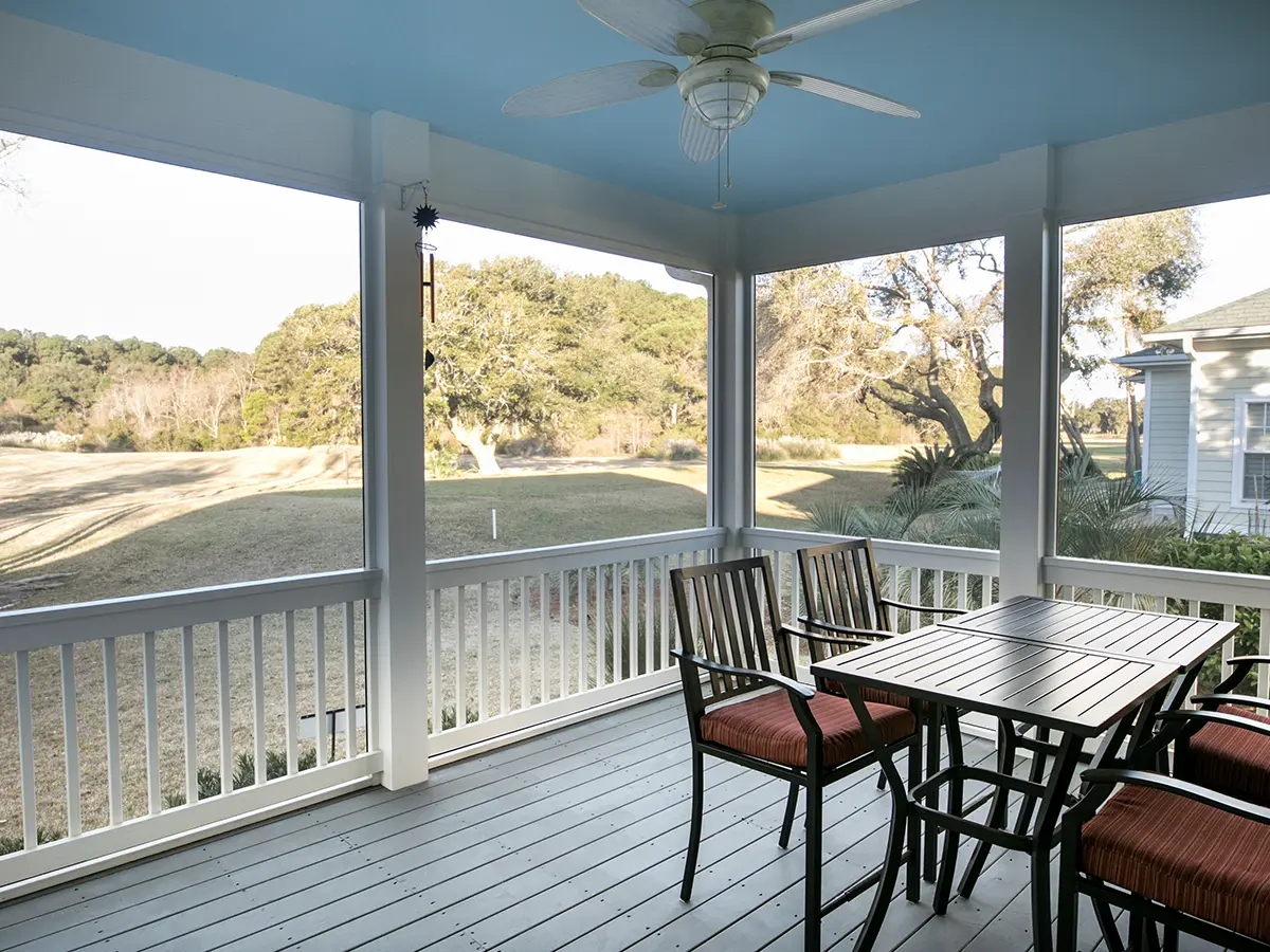 A screened-in porch with outdoor furniture and white railings